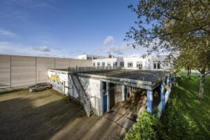 Vooraanzicht van een industrieel gebouw aan de Van der Madeweg met graffiti op de gevel en een metalen buitentrap.